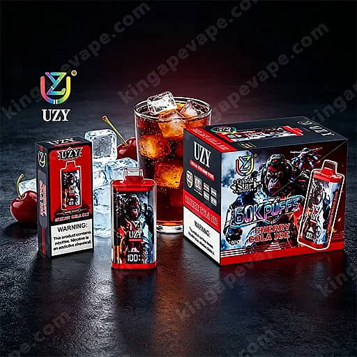 Une présentation de produits Uzy Vape comprenant une grande boîte étiquetée ' 60K Puffs Cherry Cola Ice ', une bouteille à bouchon rouge, une bouteille plus petite et une boîte d'emballage, avec des glaçons et un verre de cola en arrière-plan.