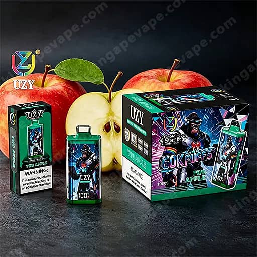 Kit de démarrage Uzy Vape avec une boîte colorée et une petite bouteille, posé sur une surface sombre avec des pommes rouges et vertes en arrière-plan.