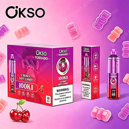 Felroze en paarse Okso Tornado Cherry Soft Candy e-vloeistofverpakking, met een grote paarse doos met het opschrift 'Okso Tornado 100K Cherry Soft Candy', een kleinere doos en een hoge fles, met een nicotinewaarschuwing en roze gomachtige vormen verspreid op de achtergrond.